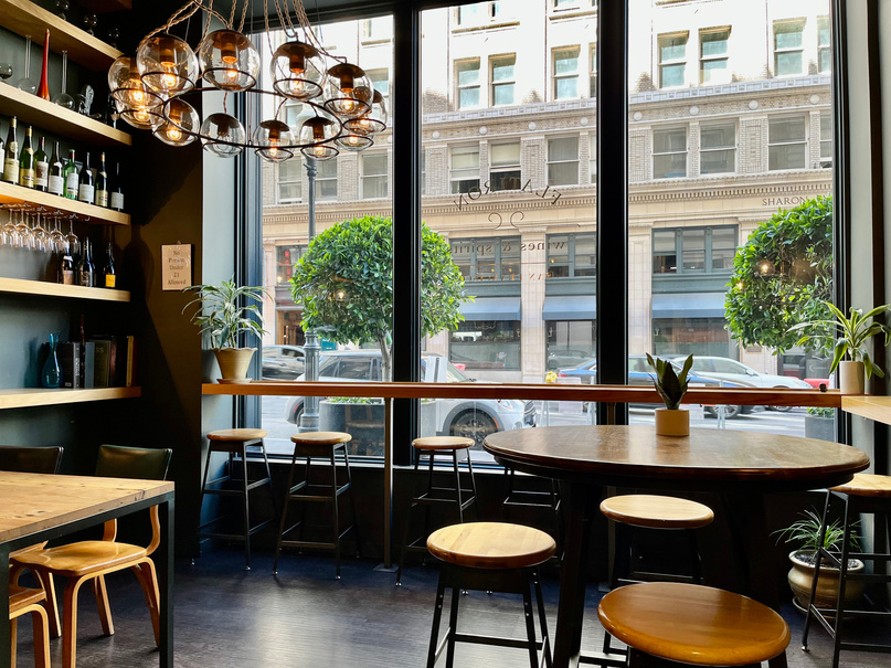 Brown Wooden Table and Chairs beside Glass Wall in a City 